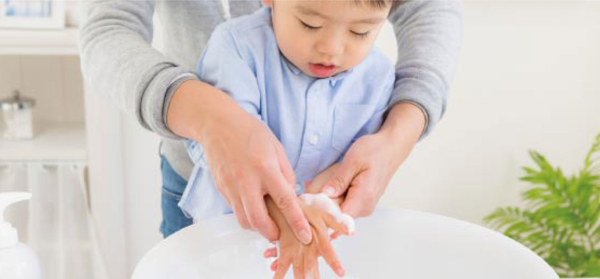 写真：親に支えられて手洗いする子供